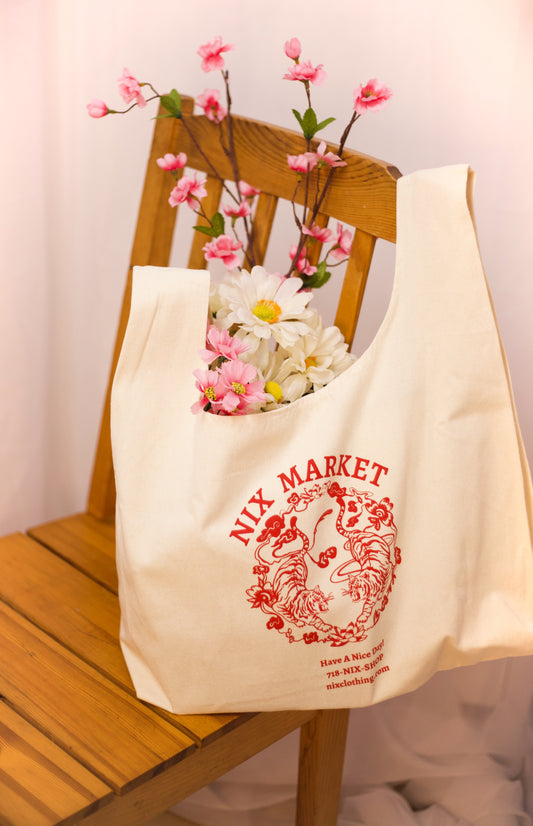 image of tote bag sitting on a chair  with flowers sticking out of the top. 